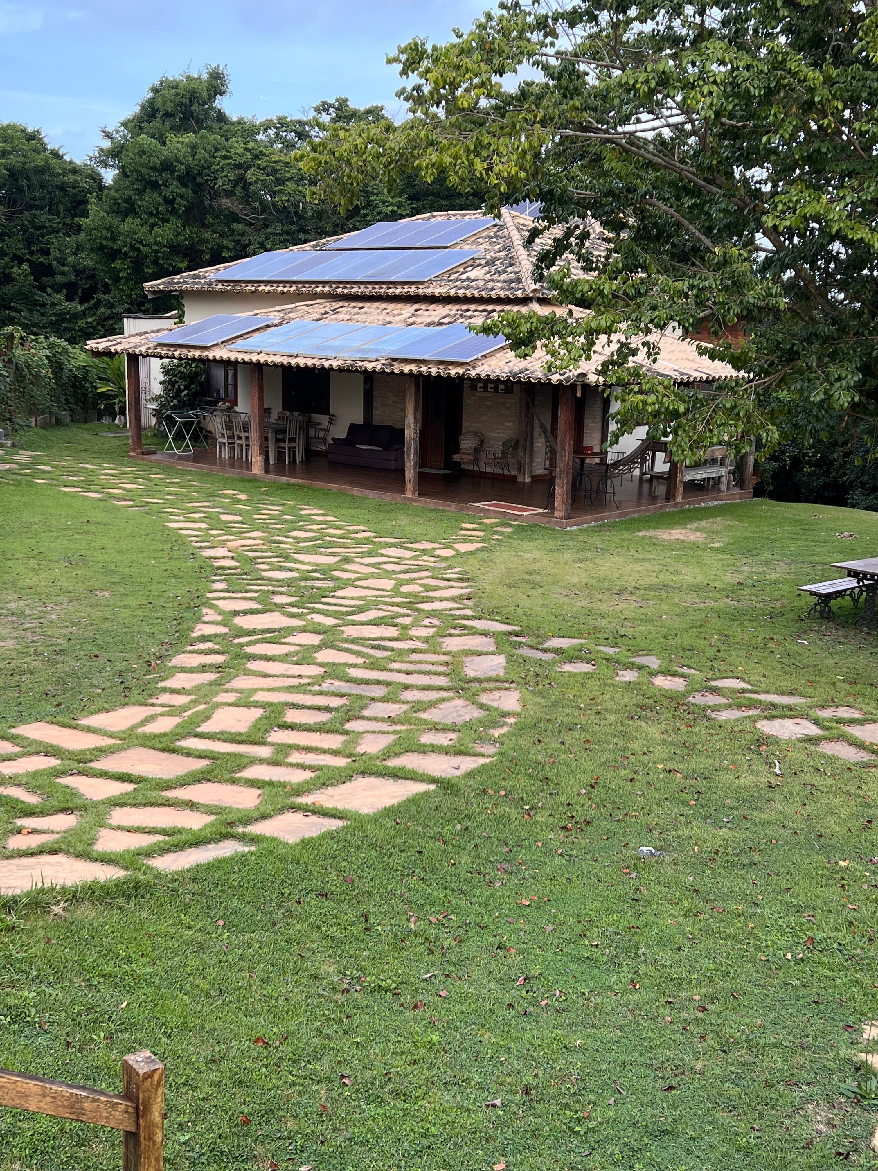 Casa de telhado colonial em meio à ampla área verde, com caminho de pedras pelo gramado